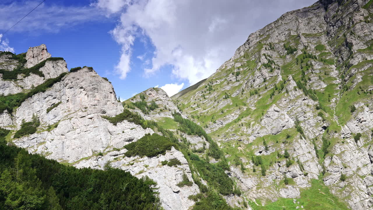 Dramatic mountain view blue skies. Lush green mountains with rocky cliffs and a bright blue sky create a stunning natural backdrop in this remote area