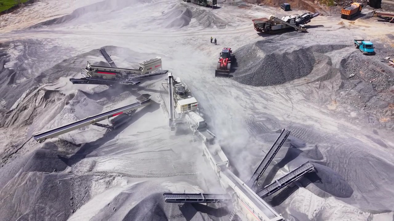 High angle view of mechanical arm discharging crushed stone onto a massive cone shaped stockpile. Close up aerial shot of conveyor belt tipping gravel.