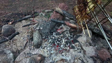 POV-shot-during-the-barbecue-with-a-grill-grate-on-which-shashlik-skewers-with-delicious-meat-and-vegetables-are-skewered-grilled-on-a-hot-coal-fire-built-with-stones