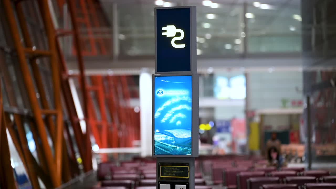 At Beijing International Airport, an illuminated charging station sign near the boarding gate allows passengers to power up electronic devices like smartphones and laptops.
