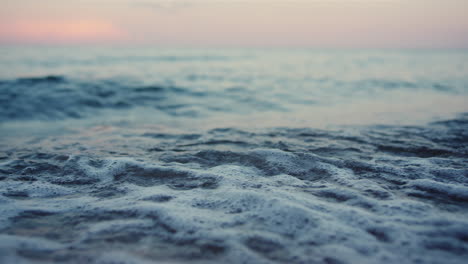 las olas azules del mar salpican la playa de arena al amanecer frío de la mañana. agua del océano tranquila