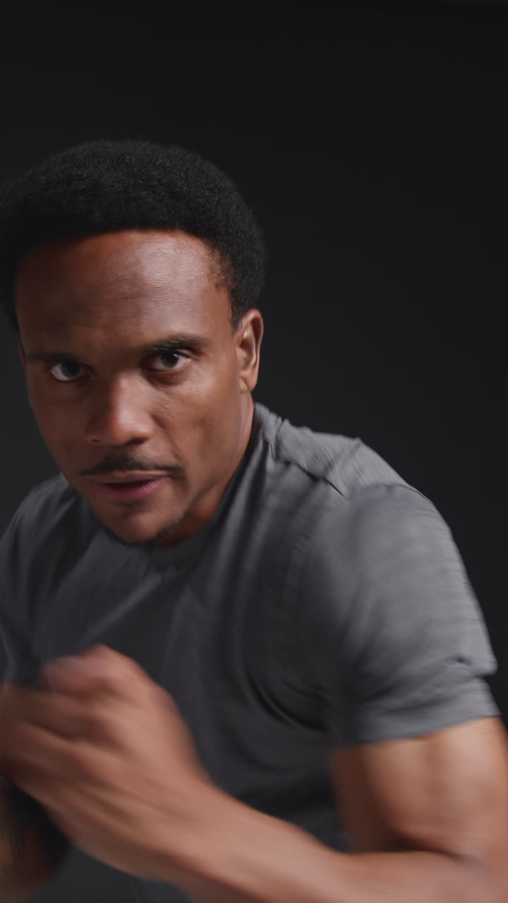 Vertical Video Close Up Studio Portrait Of Male Boxer Training In Gym Sparring Towards Camera And Warming Up Preparing For Fight Against Black Background 1