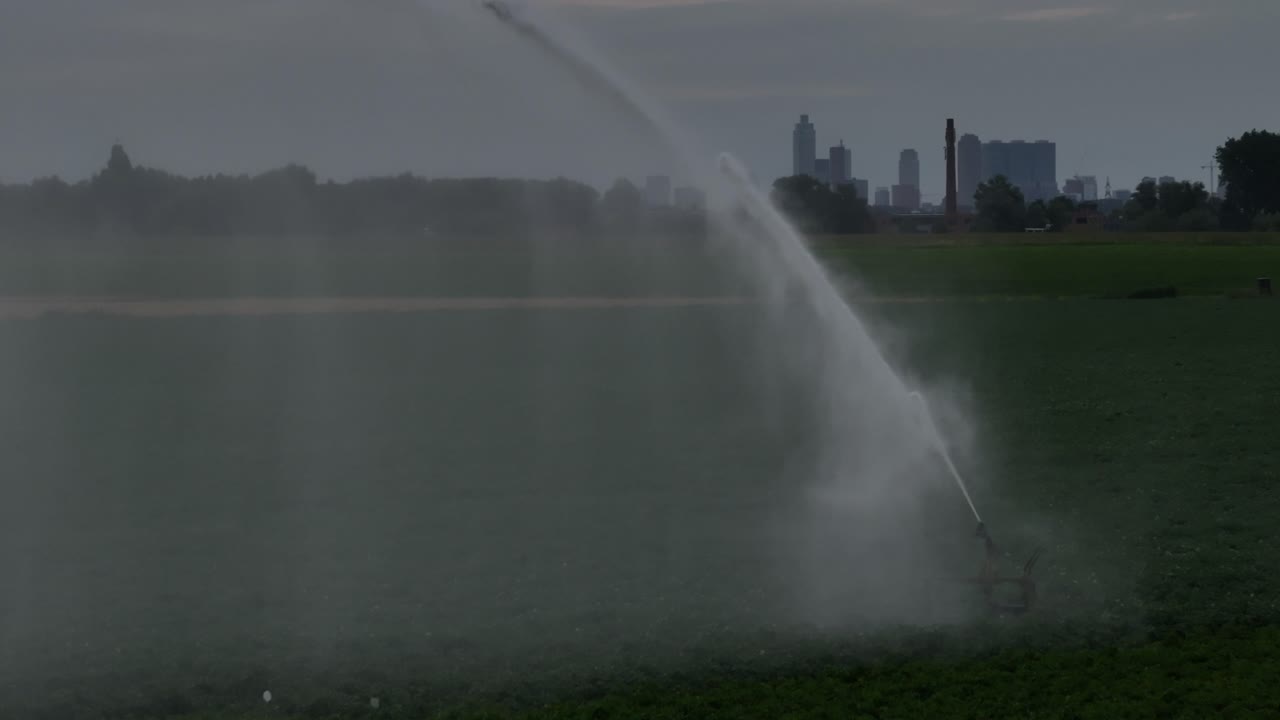 Irrigation System in a Field with City Skyline in the Background