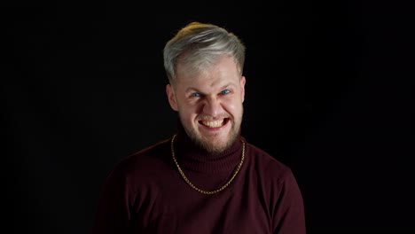 Disappointed-handsome-man-in-stylish-blouse-showing-funny-and-agressive-emotion-on-black-background