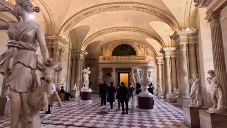 personas caminando por la galería de esculturas en el museo del louvre