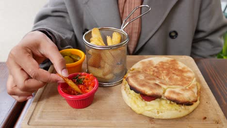 person eating a delicious sandwich with fries