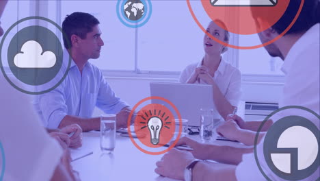 digital icons floating against team of businesspeople discussing together in a meeting at office