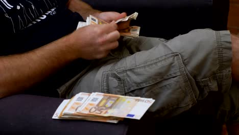 man relaxed on the armchair counts a large amount of money