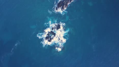 aerial tracking shot of deep blue ocean with dark cliffs in the philippines