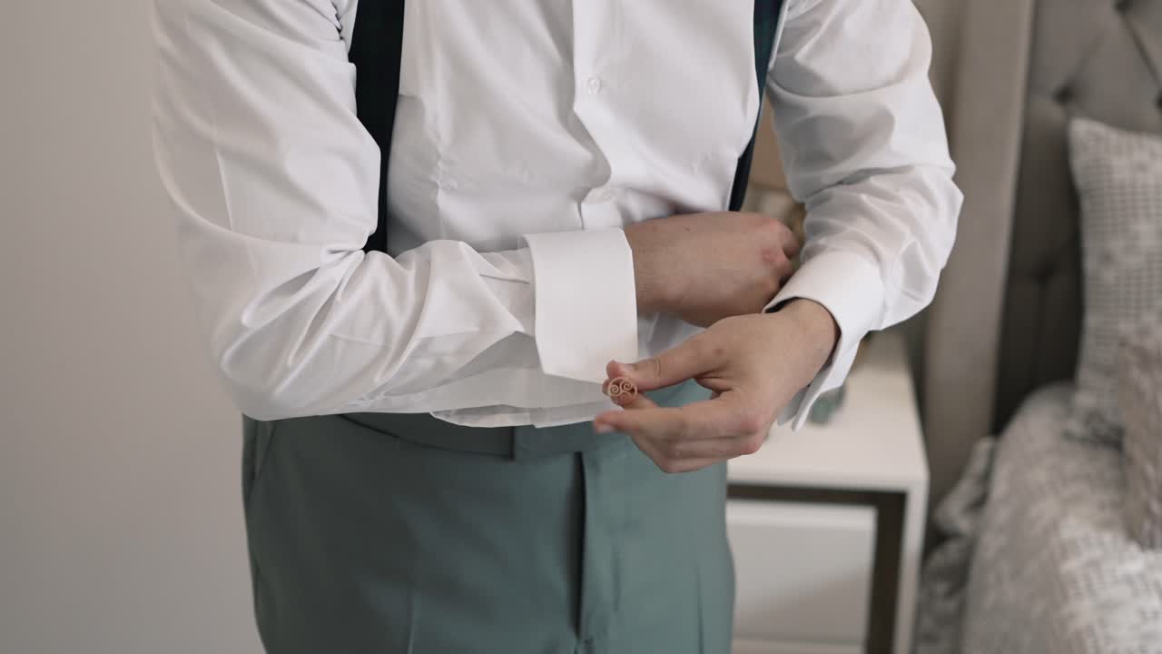 hombre ajustando el manguito de una camisa blanca, preparándose para un evento formal