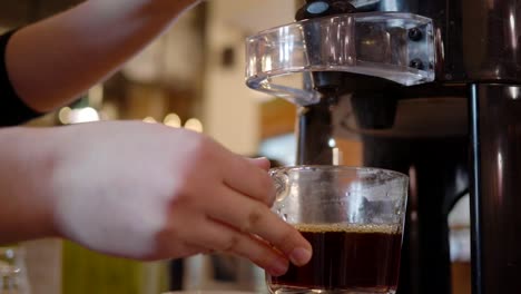 a barista pours hot coffee into a glass