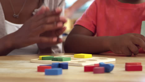 teacher and pupils using wooden shapes in montessori school