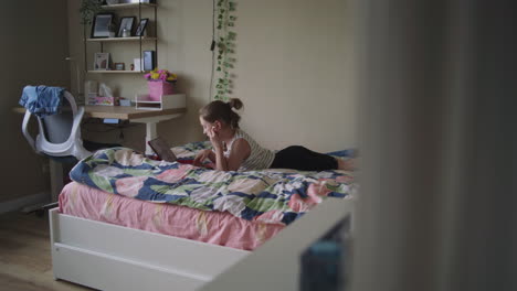 teenage girl studying on a tablet in her bedroom.