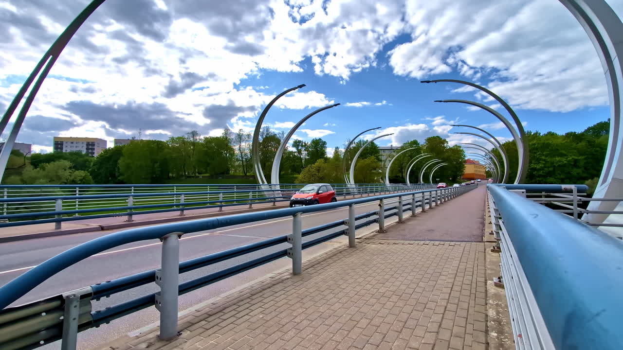 Gauja bridge in Valmiera with cars passing under curved arches on cloudy day