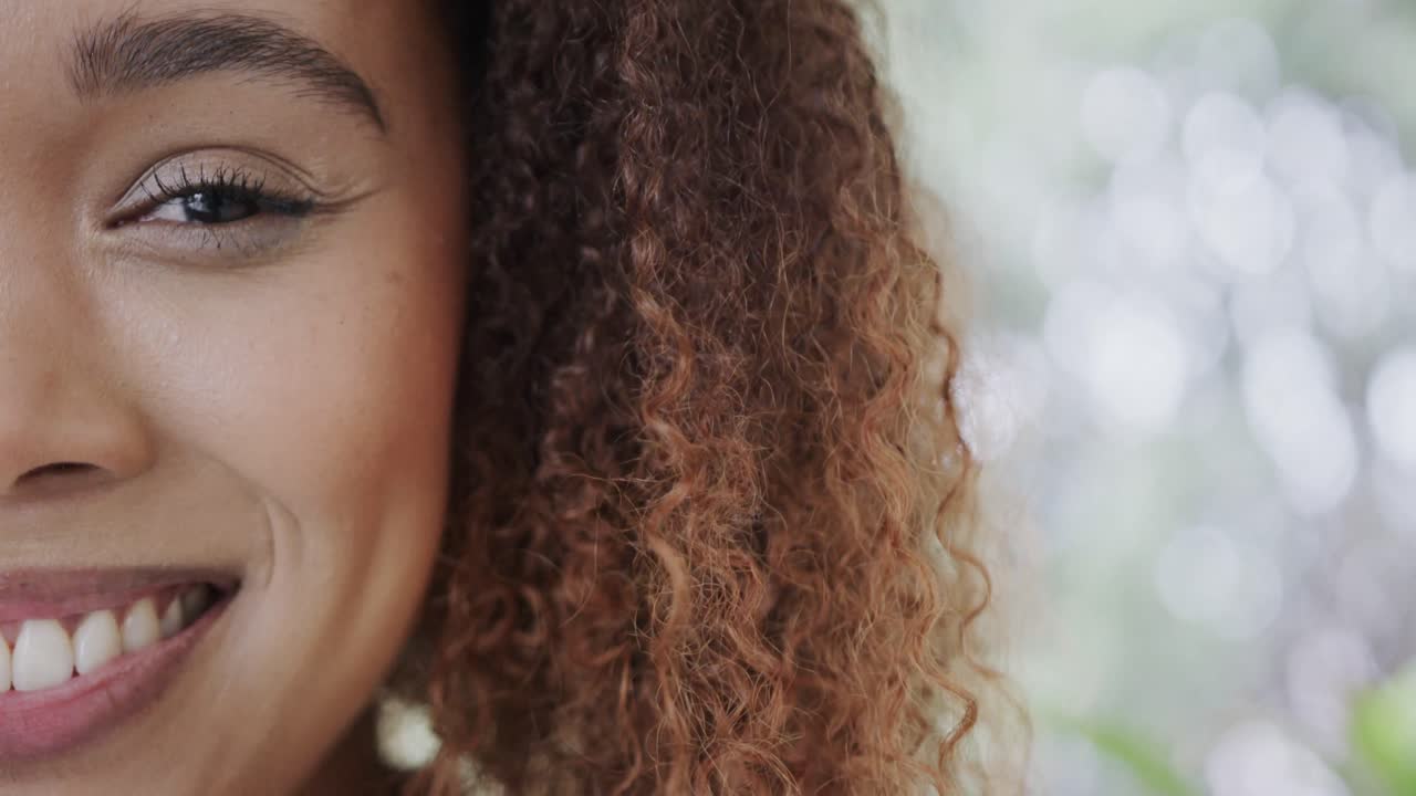 medio retrato de una feliz mujer biracial con cabello rizado sonriendo en casa, espacio de copia, cámara lenta