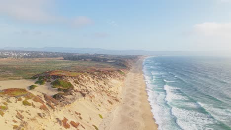 tides roll steadily along fort ord beach, their rhythm captured from the air against the backdrop of coastal bluffs