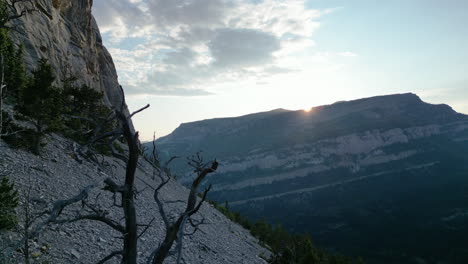 los picos del sol sobre la montaña con silueta con árbol muerto en primer plano