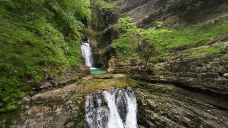 Una-Vista-Impresionante-De-La-Cascada-Ujëvara-E-Peshturës-En-Progonat,-Albania,-Cayendo-En-Cascada-Desde-Un-Acantilado-Rocoso-Rodeado-De-Exuberante-Vegetación-Y-Piscinas-De-Color-Turquesa-Claro