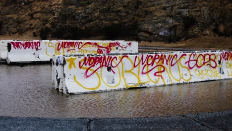 Graffiti-with-red-and-yellow-paint-on-reinforced-concrete-beams-abandoned-over-water