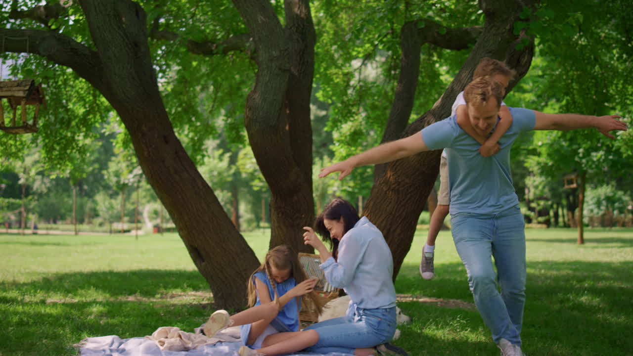 el hijo pequeño cabalga en la espalda del padre feliz. el hombre ágil sostiene al niño lindo en la espalda.
