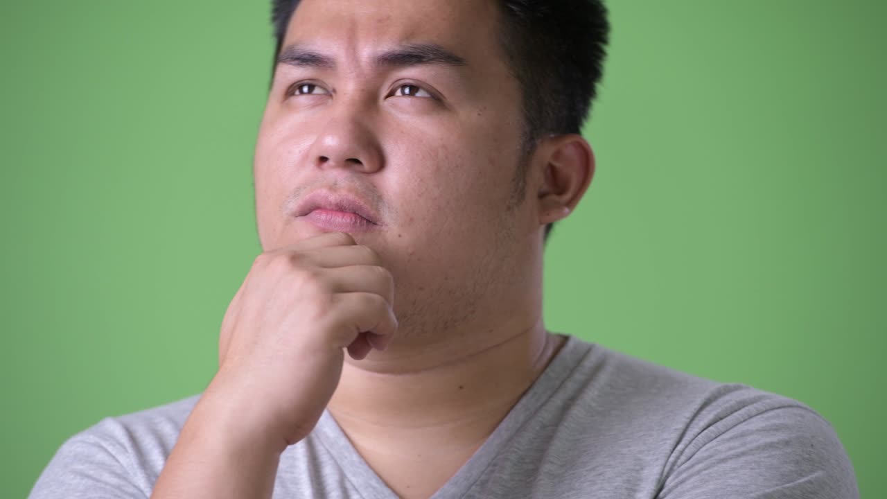 초록색 배경에 젊은 잘생긴 과체중 아시아인