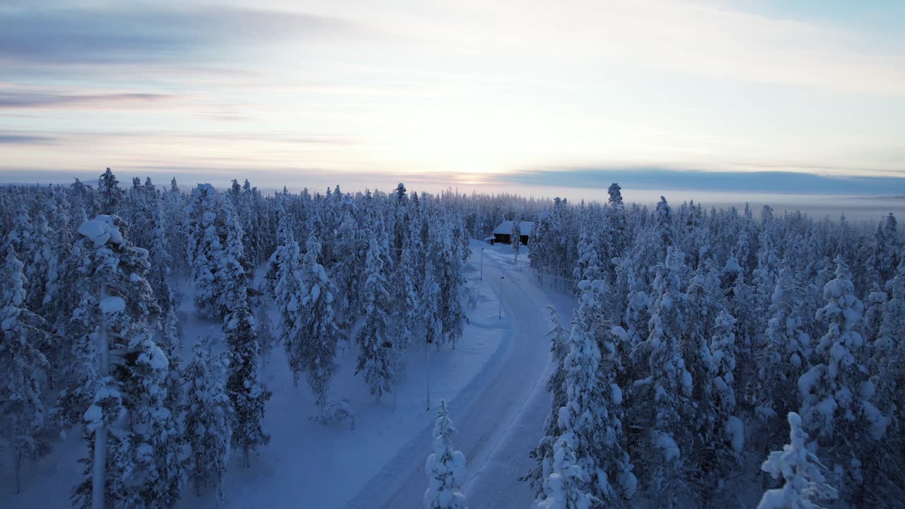 Drone flyr over snødekt vinterskog i skumringen i Lappland, Finland, Arktisk sirkel