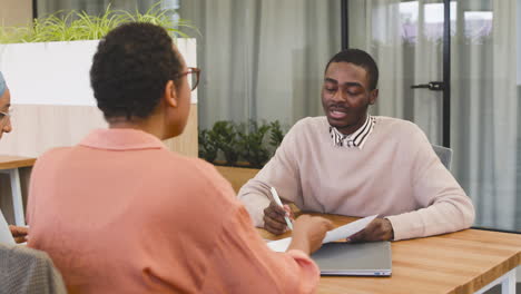 man stelt een vraag over een document aan een zakenvrouw in een sollicitatiegesprek 1