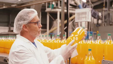 Worker-examining-a-bottle-in-factory