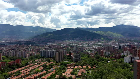 Drone-Shot-of-the-city-of-Medellín,-Colombia-showing-mountains-and-the-city-on-a-sunny-cloudy-afternoon