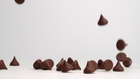 unwrapped hershey chocolate kisses falling and bouncing around on white table top in slow motion