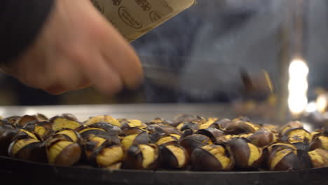 closeup of hands selling hot chestnuts on turkish market in istanbul