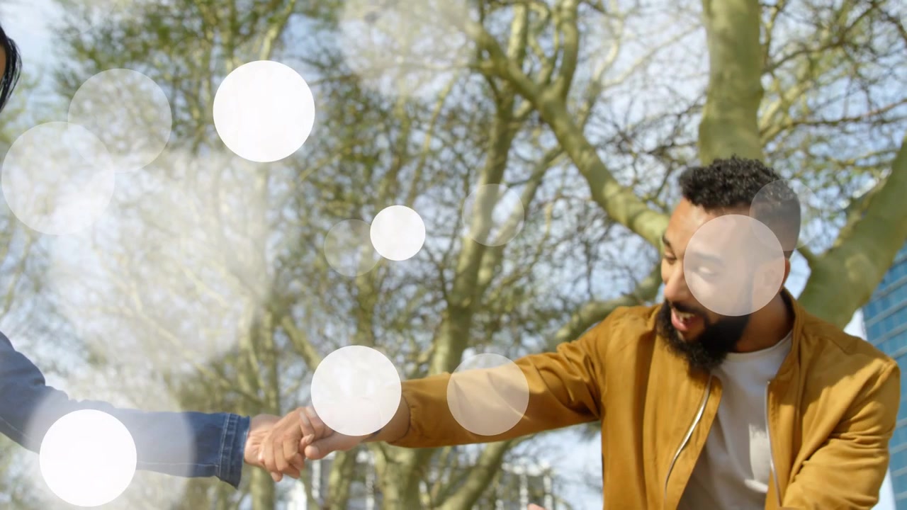 Donna che si protende verso un uomo che entra, tenendosi per mano, con un effetto bokeh fluttuante che si posa sulle mani che si uniscono, per annunci pubblicitari.