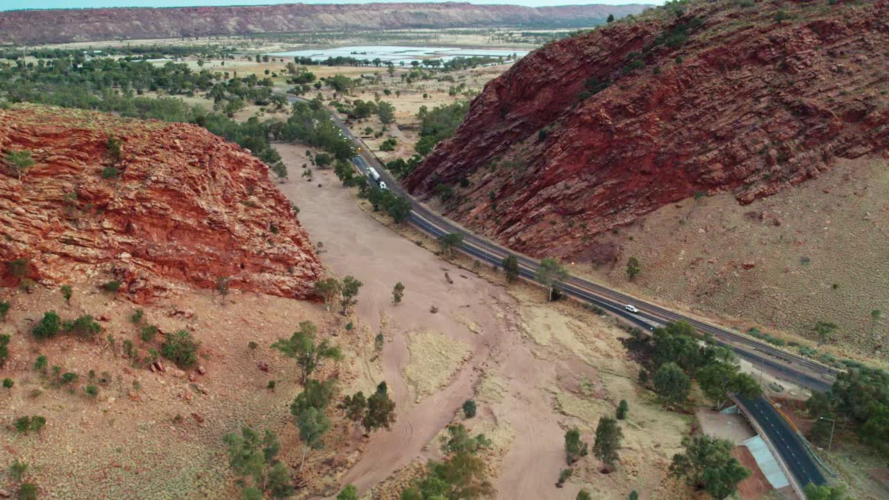 Reversing drone footage over Heavitree Gap and The Gap, a suburb of Alice Springs, Mparntwe, with The Todd River and Heavitree Gap in the distance. Northern Territory, Australia. August 2022.
