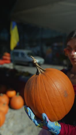 mujer inspeccionando una calabaza en un mercado