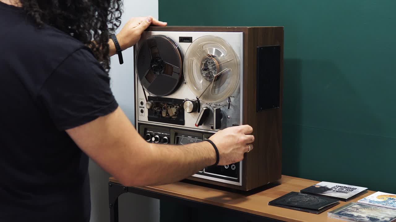 plano medio del hombre arreglando el viejo carrete de audio magnético vintage a la cinta en el estudio de grabación