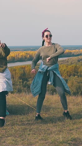 positive girl hikers have party near blue tent in tourist camp on steep river bank in autumn evening slow motion