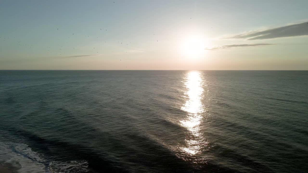 Aerial drone rising over Atlantic Ocean during sunrise golden hour at Myrtle Beach, South Carolina