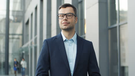 portrait of smiling businessman in glasses in the street and looking to the camera