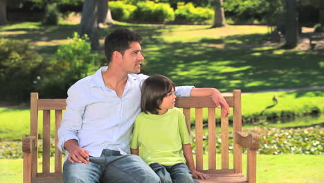 father sitting with his son on a park bench