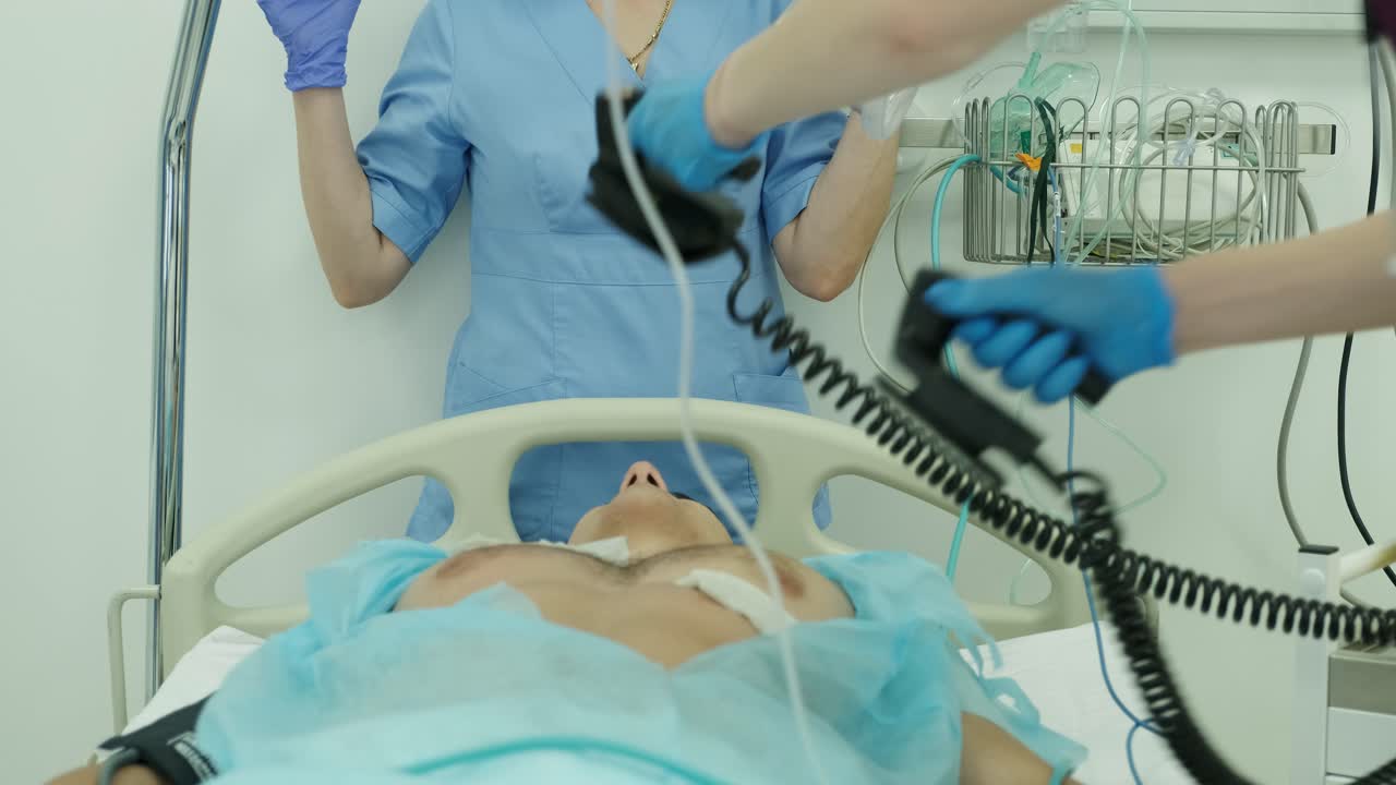 los médicos hacen reanimación a un paciente masculino en la sala de emergencias. masaje cardíaco. desfibrilación.