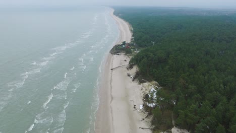 Luftaufnahme-Der-Ostseeküste-An-Einem-Bewölkten-Wintertag,-Ein-Haus-Am-Strand-Mit-Weißem-Sand,-Küstenerosion,-Klimaveränderungen,-Breiter-Drohnenschuss,-Der-Sich-Vorwärts-Bewegt,-Kamera-Nach-Unten-Geneigt