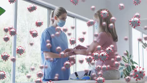 Animation-of-covid-virus-cells-over-caucasian-senior-woman-and-nurse-wearing-face-masks-massaging