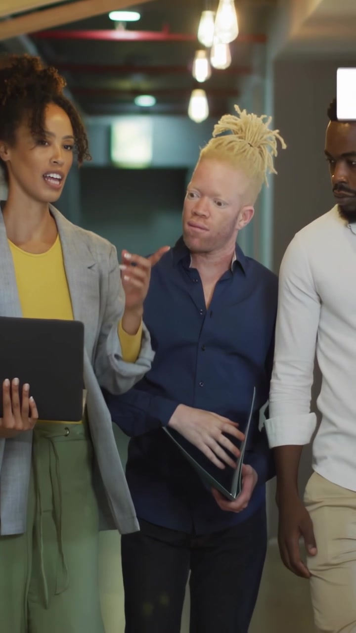 Team di marketing che cammina nel corridoio, una donna presenta un laptop mentre "mi piace" e conteggi di messaggi fluttuanti si aggiornano.