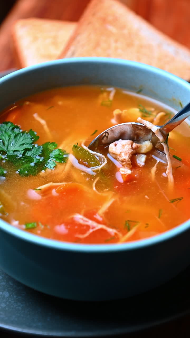 Hønsekødssuppe med tomat og gulerod. Orangefarvet bouillon med strimlet kylling, tomater og gulerødder tilsat urter