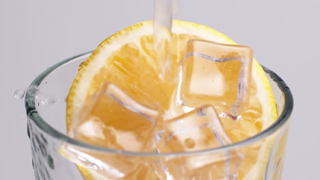 cold fresh sparkling water pouring into a glass with ice and lemon slices-3