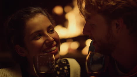 pareja hablando bebiendo vino en la fecha de primer plano. marido esposa sonriendo relajarse junto a la chimenea
