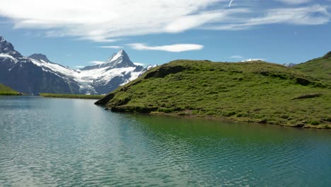 dramatic revealing aerial shot of blue mountain lake in the swiss alps with dramatic snow covered mountain peaks backdrop, bachalpsee grindelwald first, switzerland