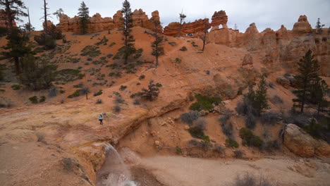 Mujer-Caminando-Por-Encima-De-Una-Pequeña-Cascada-Bajo-Formaciones-Rocosas-Hoodoo-En-El-Parque-Nacional-Bryce-Canyon,-Utah,-EE.UU.