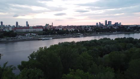 Filmische-Drohnenaufnahmen-Der-Warschauer-Skyline-Mit-Der-Weichsel-Und-Einer-Verkehrsreichen-Brücke-Mit-Großer-Kurve,-Um-Die-Stadt-Freizugeben