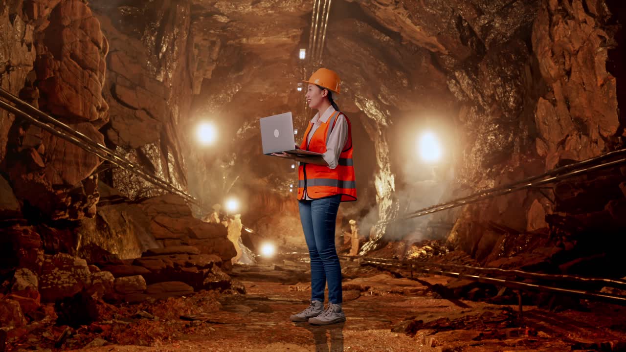 Female Engineer Working in a Mine Tunnel with a Laptop
